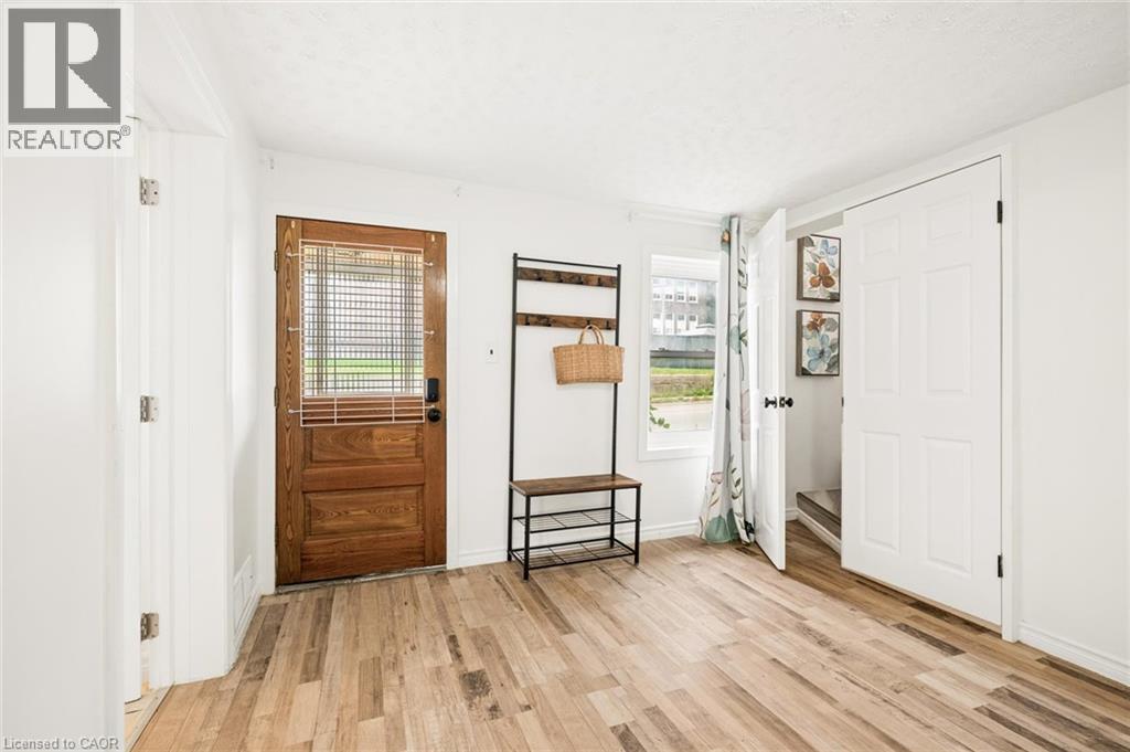 Wood-finish flooring, white walls, wood entry door with window, white interior doors, and a window with natural light - 77 Beverly Street, Cambridge, ON