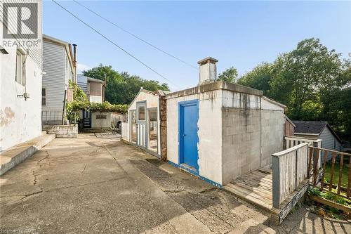 Concrete driveway with a detached block structure, a separate greenhouse-style building, and a wood-slat railing - 77 Beverly Street, Cambridge, ON 