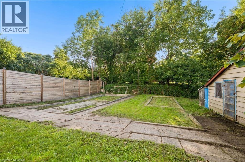 Expansive yard featuring a privacy fence, concrete pathways, and established garden beds - 77 Beverly Street, Cambridge, ON