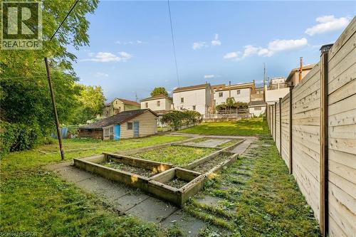 Expansive yard featuring a privacy fence, multiple raised garden beds, a shed, and concrete pathways - 77 Beverly Street, Cambridge, ON 
