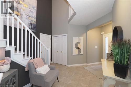 Two-story foyer featuring a white balustrade staircase, a double-door closet, and tile flooring - 1200 Dunbar Road, Cambridge, ON 