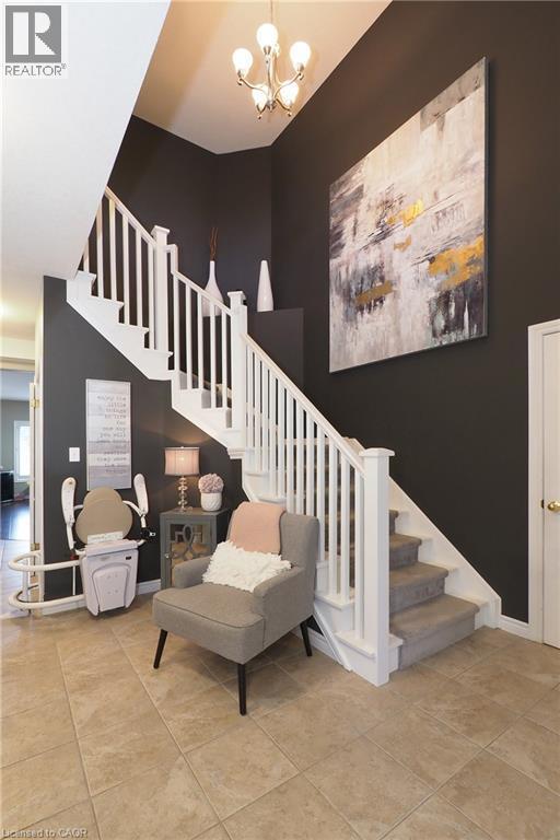 Foyer featuring tile flooring, a staircase with white balusters, and a contemporary chandelier - 1200 Dunbar Road, Cambridge, ON