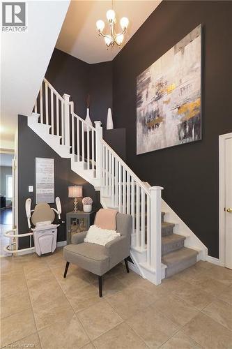 Foyer featuring tile flooring, a staircase with white balusters, and a contemporary chandelier - 1200 Dunbar Road, Cambridge, ON 
