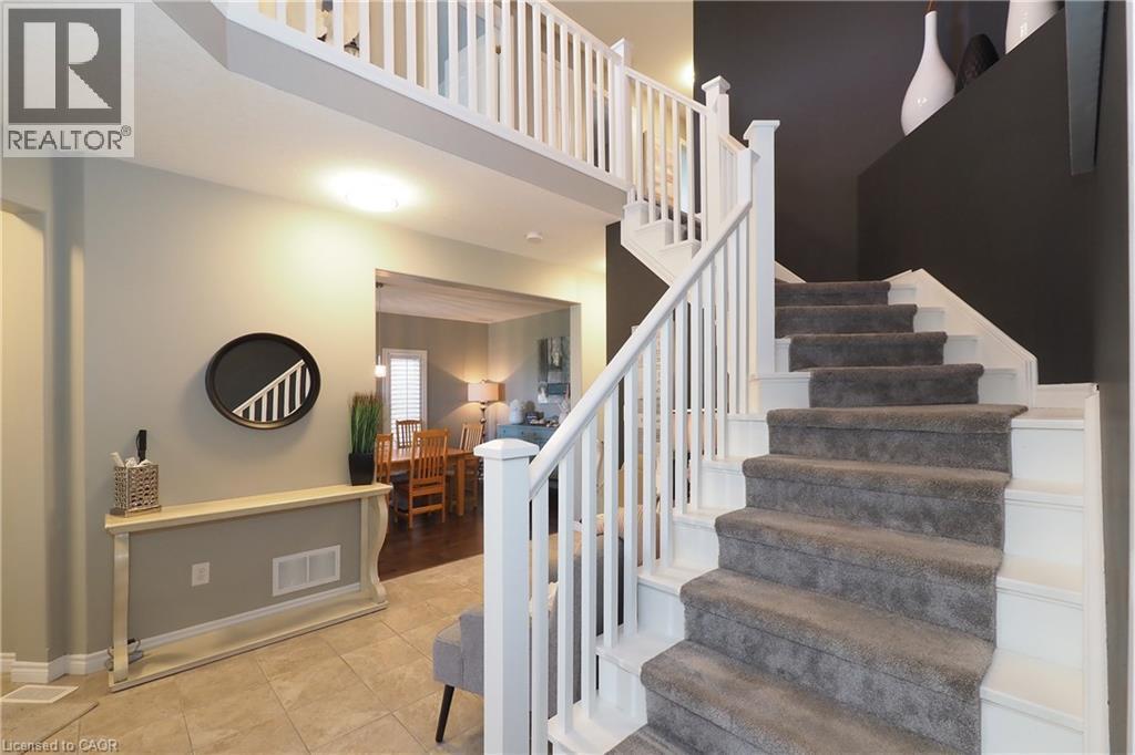 Tiled flooring entryway with a staircase featuring carpeted treads and white wood balusters - 1200 Dunbar Road, Cambridge, ON