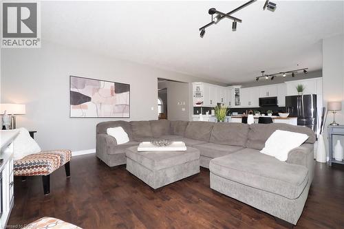 Open-concept living space featuring wood-finish flooring, recessed lighting, track lighting, and a kitchen with white cabinetry and black appliances - 1200 Dunbar Road, Cambridge, ON 