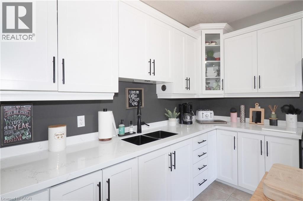 White cabinetry with matte black hardware, dual basin sink with matte black faucet, light-toned countertops, and recessed lighting - 1200 Dunbar Road, Cambridge, ON