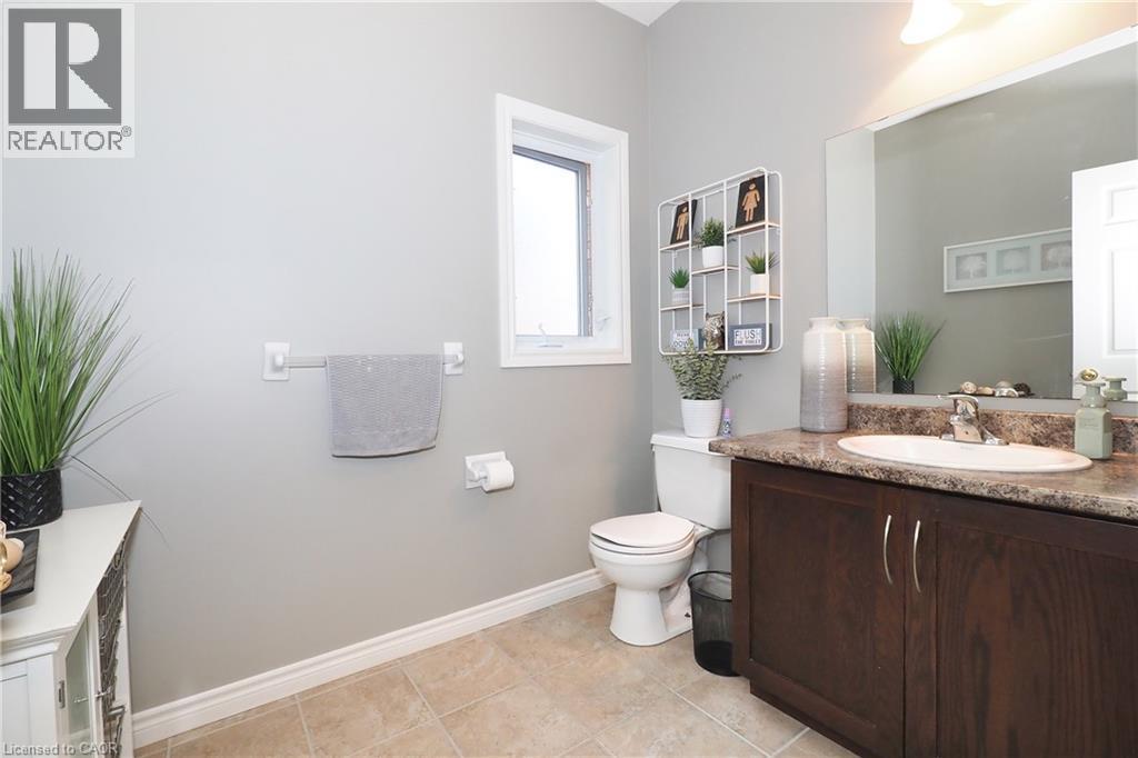 Bathroom featuring a dark wood-finish vanity, integrated basin, and a wall-mounted mirror - 1200 Dunbar Road, Cambridge, ON
