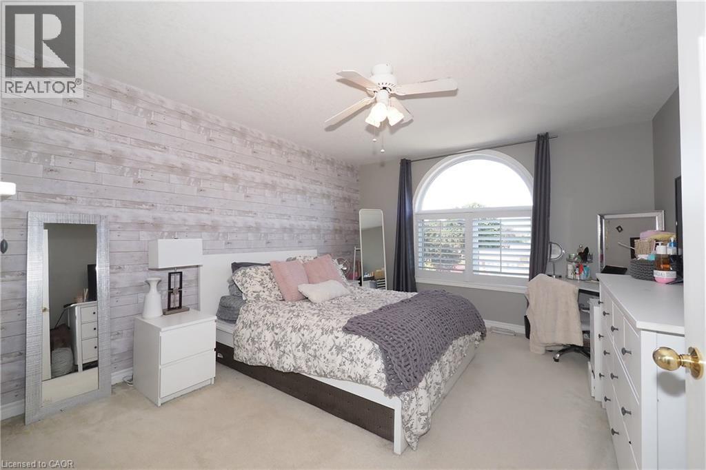 Shiplap accent wall, arched window with plantation shutters, ceiling fan, and carpeted flooring - 1200 Dunbar Road, Cambridge, ON
