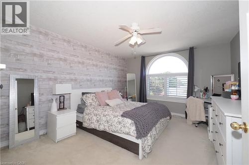 Shiplap accent wall, arched window with plantation shutters, ceiling fan, and carpeted flooring - 1200 Dunbar Road, Cambridge, ON 