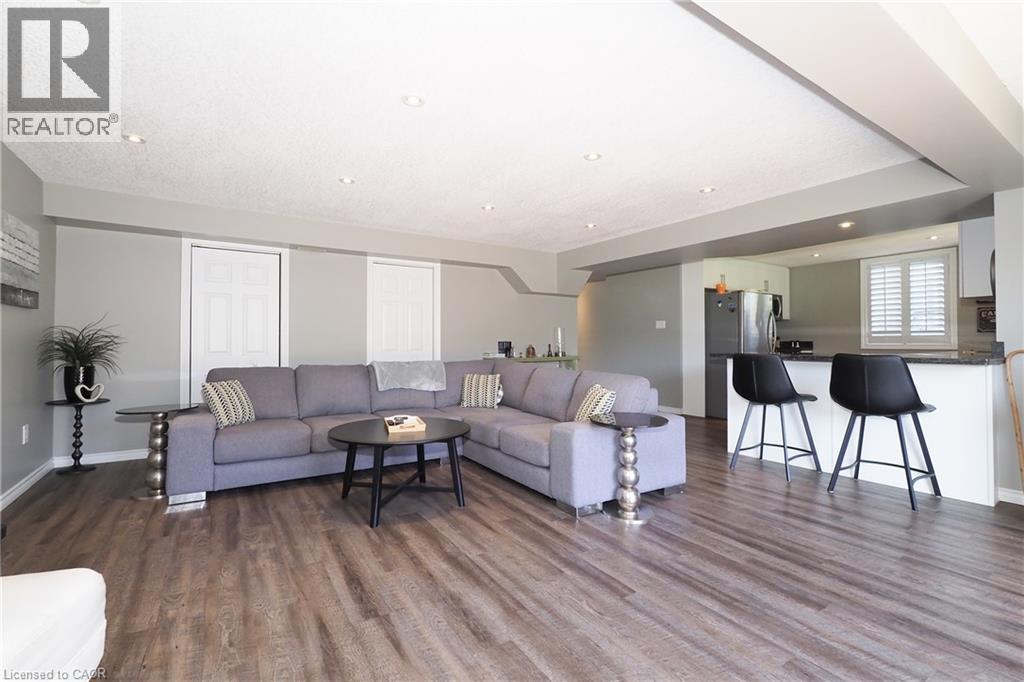 Open-concept living area featuring wood-finish flooring, recessed lighting, and a breakfast bar with stone countertops - 1200 Dunbar Road, Cambridge, ON