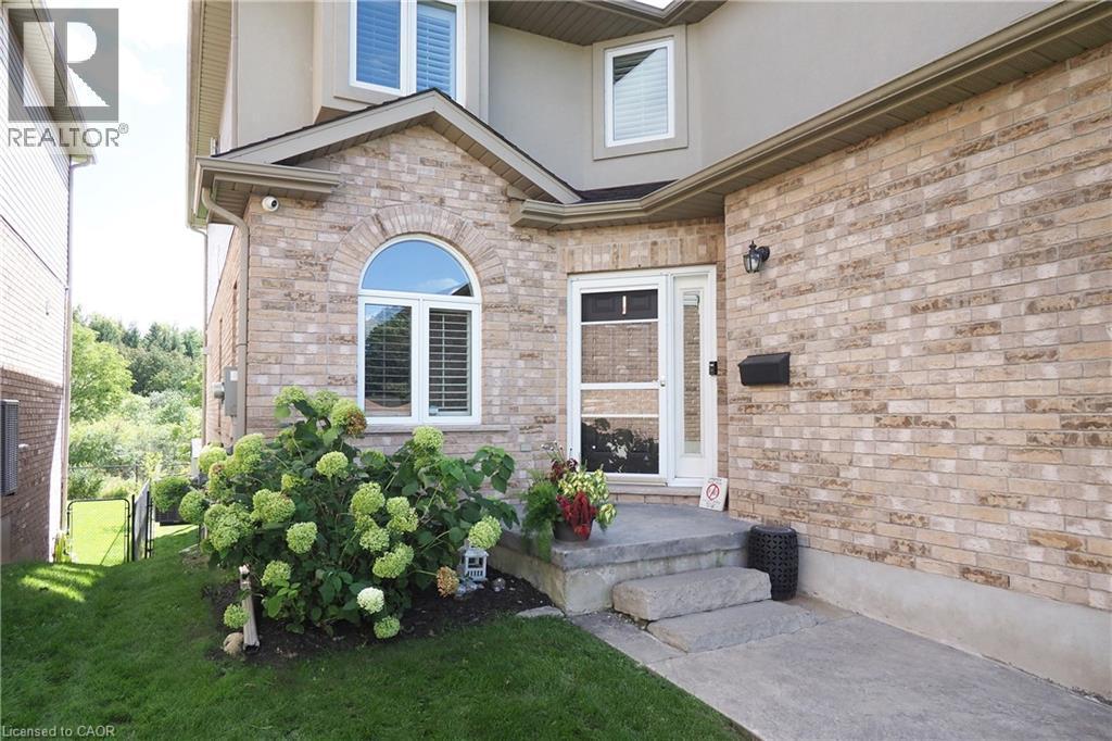 Brick exterior with arched window, concrete steps, and a landscaped garden bed - 1200 Dunbar Road, Cambridge, ON