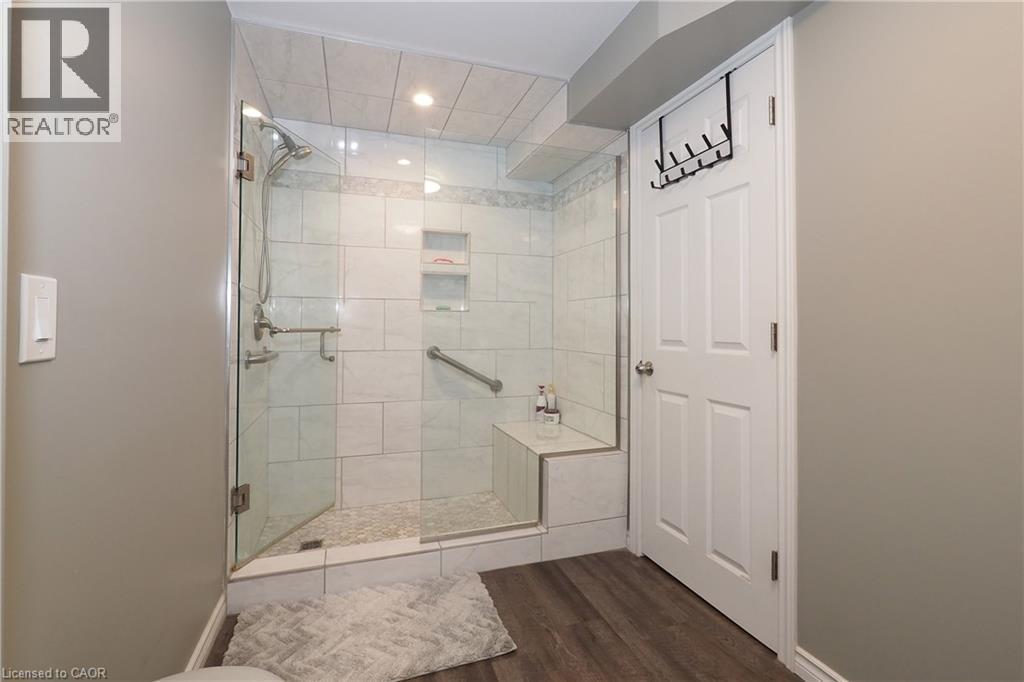 Walk-in shower with clear glass enclosure, integrated bench seating, and tiled walls - 1200 Dunbar Road, Cambridge, ON
