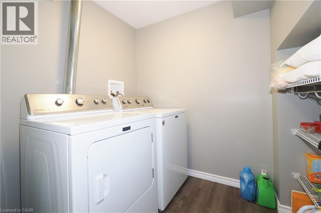 Laundry area featuring wood-finish flooring, white appliances, and built-in wire shelving - 1200 Dunbar Road, Cambridge, ON