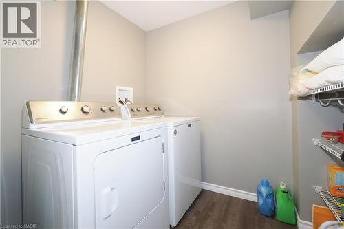 Laundry area featuring wood-finish flooring, white appliances, and built-in wire shelving - 1200 Dunbar Road, Cambridge, ON 