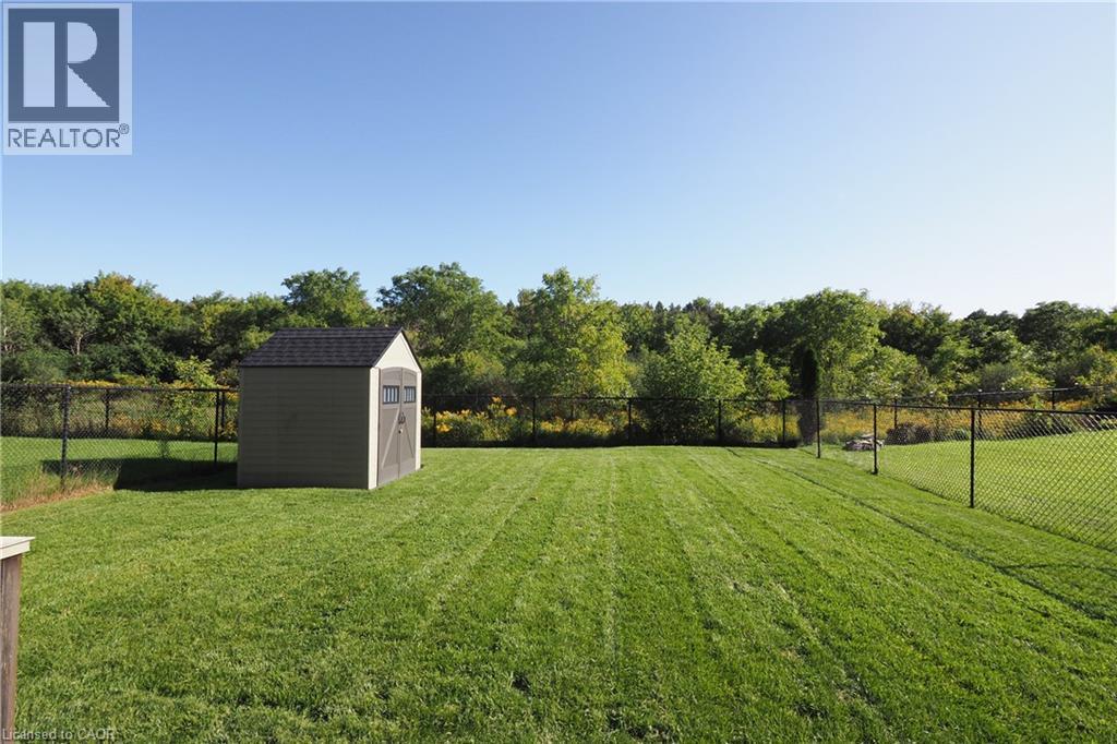 Expansive grassy yard with a storage shed, chain-link fencing, and mature perimeter trees - 1200 Dunbar Road, Cambridge, ON