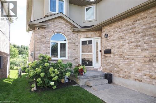 Brick exterior with arched window, concrete steps, and a landscaped garden bed - 1200 Dunbar Road, Cambridge, ON 