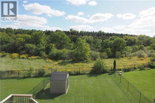 Expansive green lawn with a storage shed, wood deck, and chain-link fencing, bordered by mature trees and natural vegetation - 1200 Dunbar Road, Cambridge, ON 