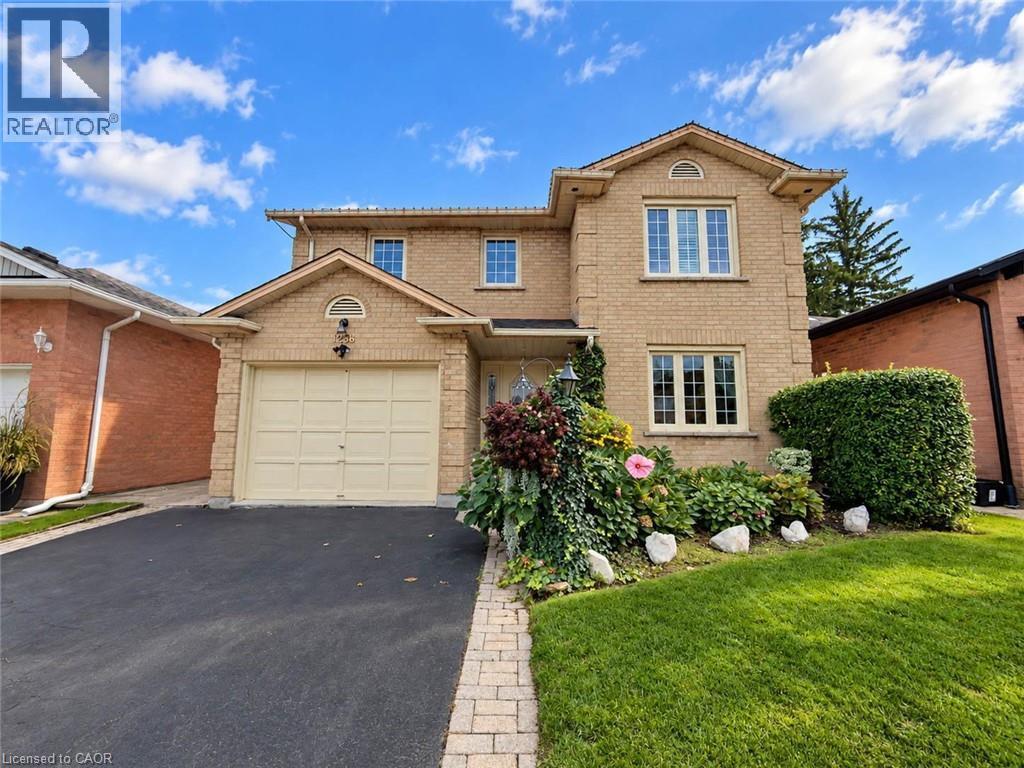 Brick exterior with multiple windows, attached garage with carriage-style door, paved driveway, and established landscaping - 1236 Thorpe Road, Burlington, ON