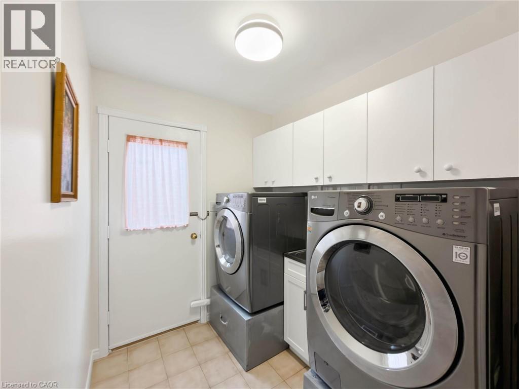 Laundry area featuring tile flooring, white upper cabinetry with knob hardware, and a ceiling-mounted light fixture - 1236 Thorpe Road, Burlington, ON