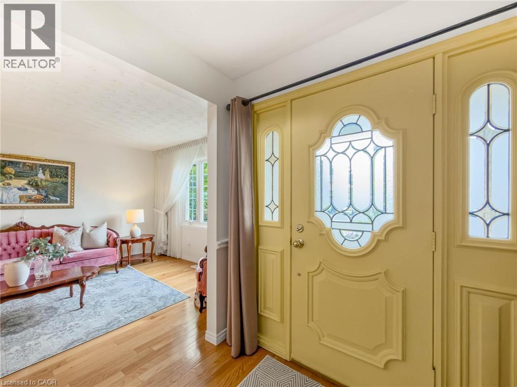 Entryway with decorative leaded glass door and sidelights, wood-finish flooring, and white walls - 1236 Thorpe Road, Burlington, ON