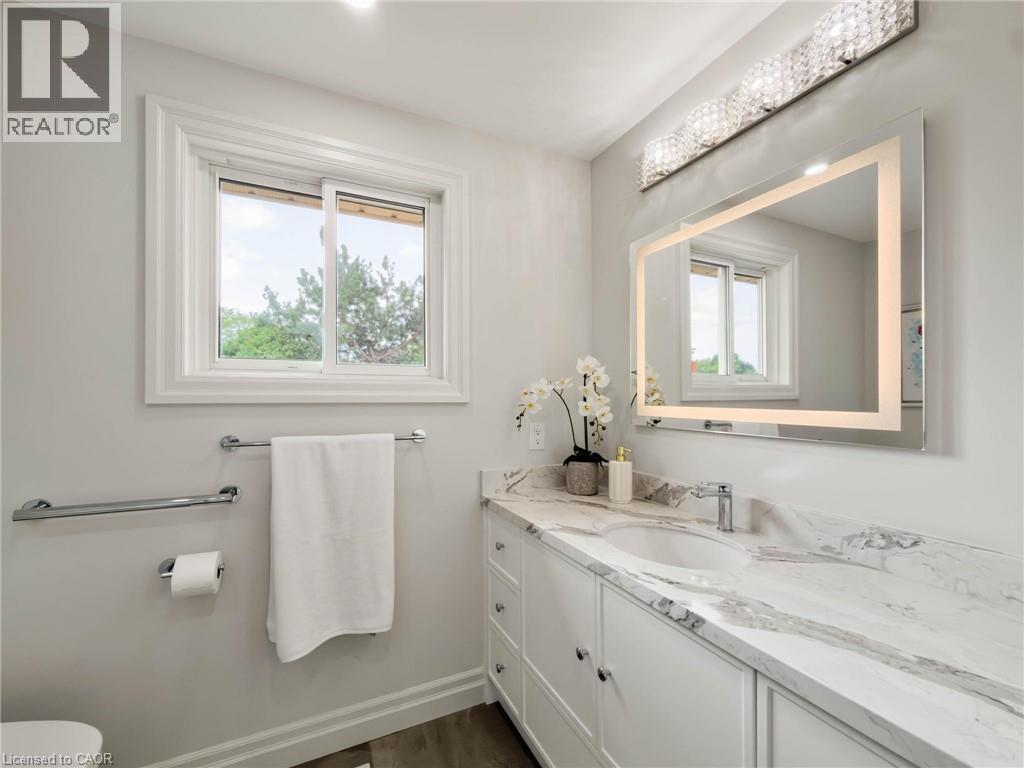 Vanity with integrated sink, stone-finish countertop, and white cabinetry - 1236 Thorpe Road, Burlington, ON