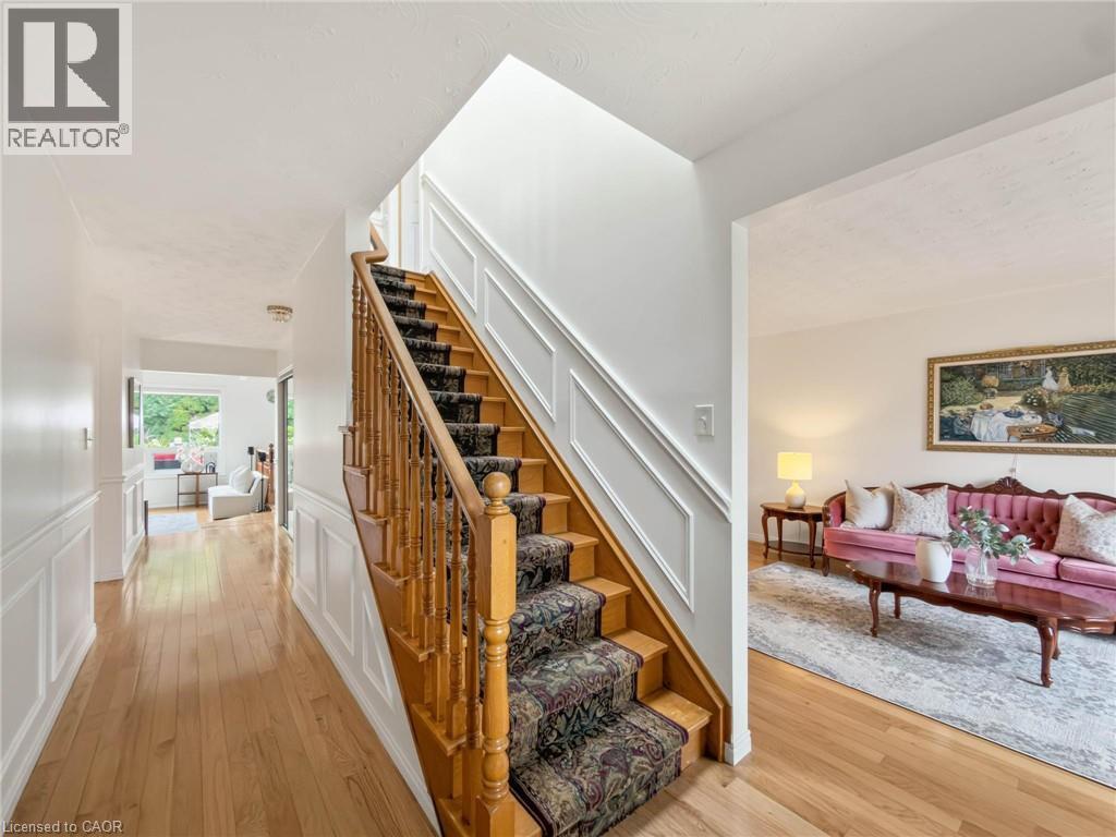 Hardwood flooring, wood staircase with carpeted treads, decorative wall paneling, and a bright interior - 1236 Thorpe Road, Burlington, ON