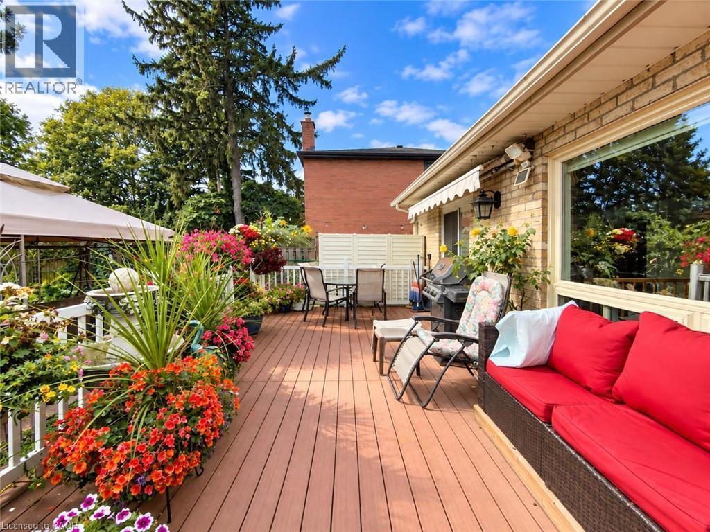 Expansive wood-finish deck with white railing, brick exterior, and large picture window - 1236 Thorpe Road, Burlington, ON