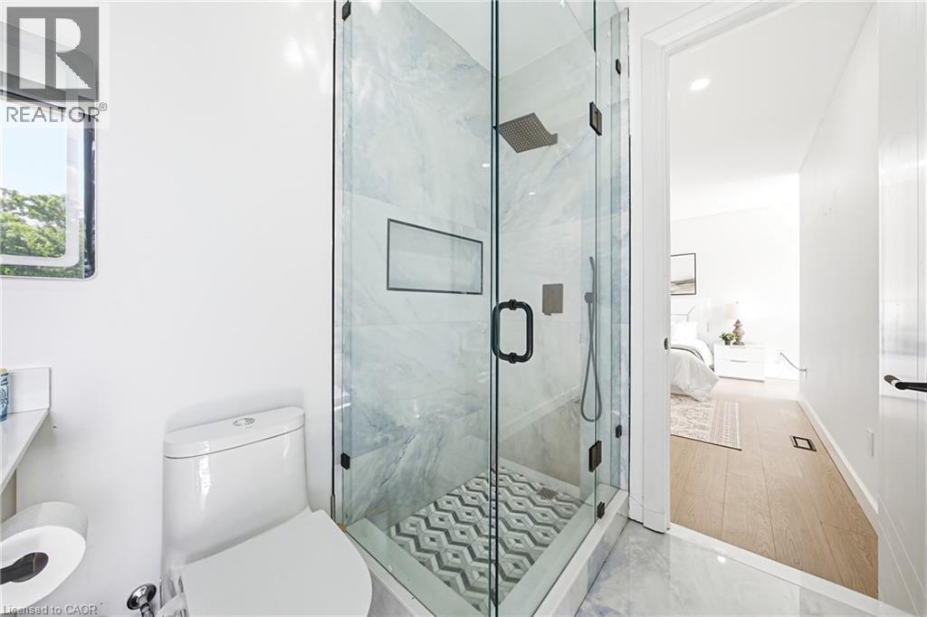 Glass-enclosed shower with a geometric tile floor and a rainfall showerhead - 4511 Guelph Line, Burlington, ON