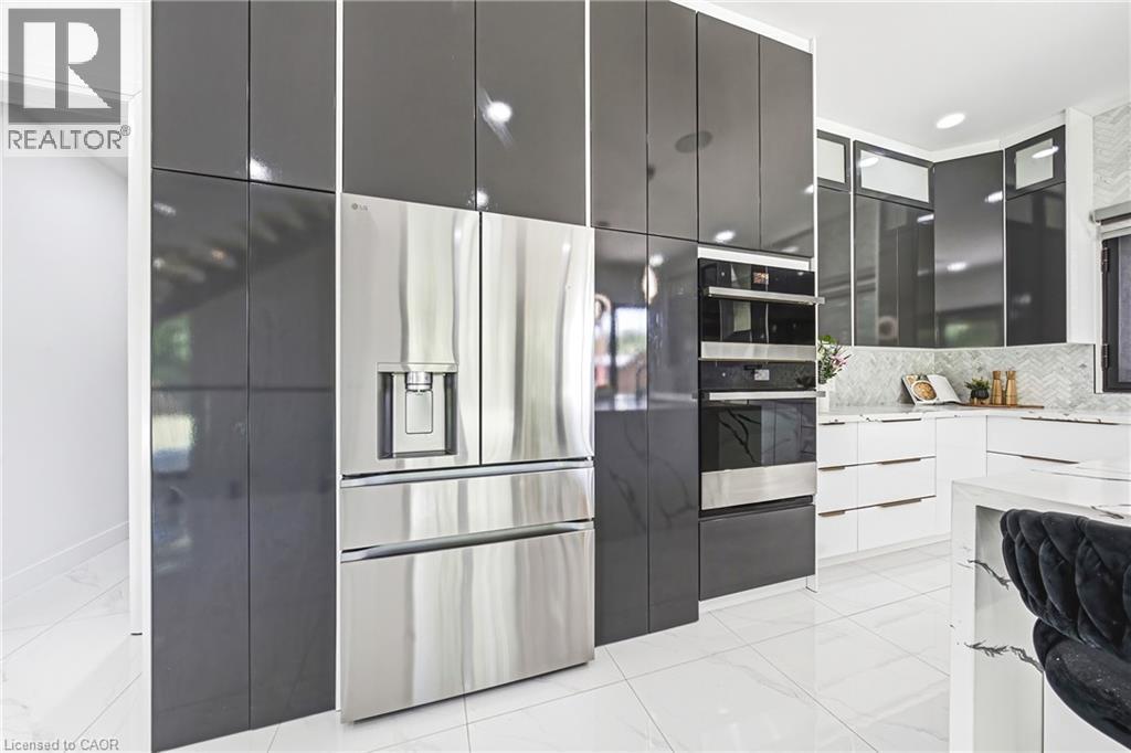 Contemporary kitchen featuring high-gloss gray cabinetry, stainless steel multi-door refrigerator with ice and water dispensers, white quartz countertops, integrated wall-mounted oven and microwave co - 4511 Guelph Line, Burlington, ON