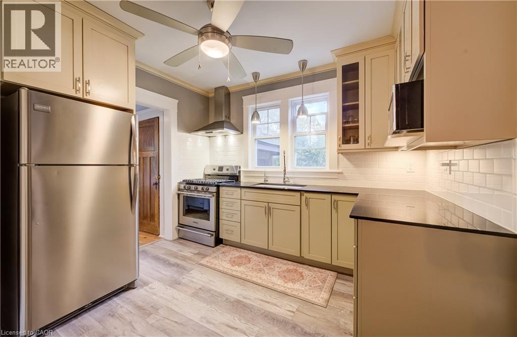 Kitchen featuring stainless steel appliances, wood-finish flooring, recessed lighting, and a subway tile backsplash - 90 Brock Street, Kitchener, ON