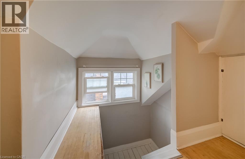 Attic space featuring sloped ceilings, a double window, wood-finish flooring, and painted walls - 90 Brock Street, Kitchener, ON