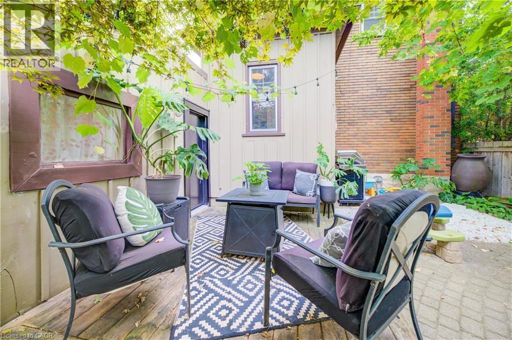 Expansive outdoor space featuring a composite wood deck, brick-paved patio, gravel landscaping, and lush overhead foliage - 90 Brock Street, Kitchener, ON