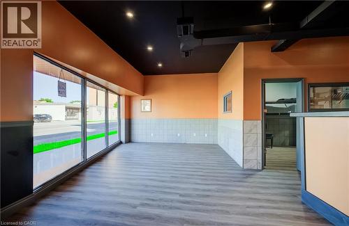 Expansive storefront windows, wood-finish flooring, recessed ceiling lighting, two-tone wall finishes, and a built-in counter - 1118 King Street E, Cambridge, ON 
