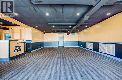 Wood-finish flooring, recessed lighting, exposed ceiling ductwork, built-in counter with sink, and brick-pattern wall accents - 1118 King Street E, Cambridge, ON 