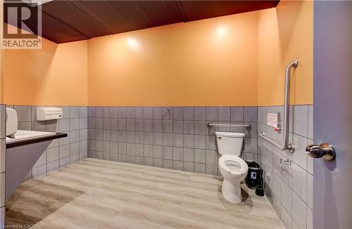 Light wood-finish flooring, half-tiled walls, and a white toilet - 1118 King Street E, Cambridge, ON 