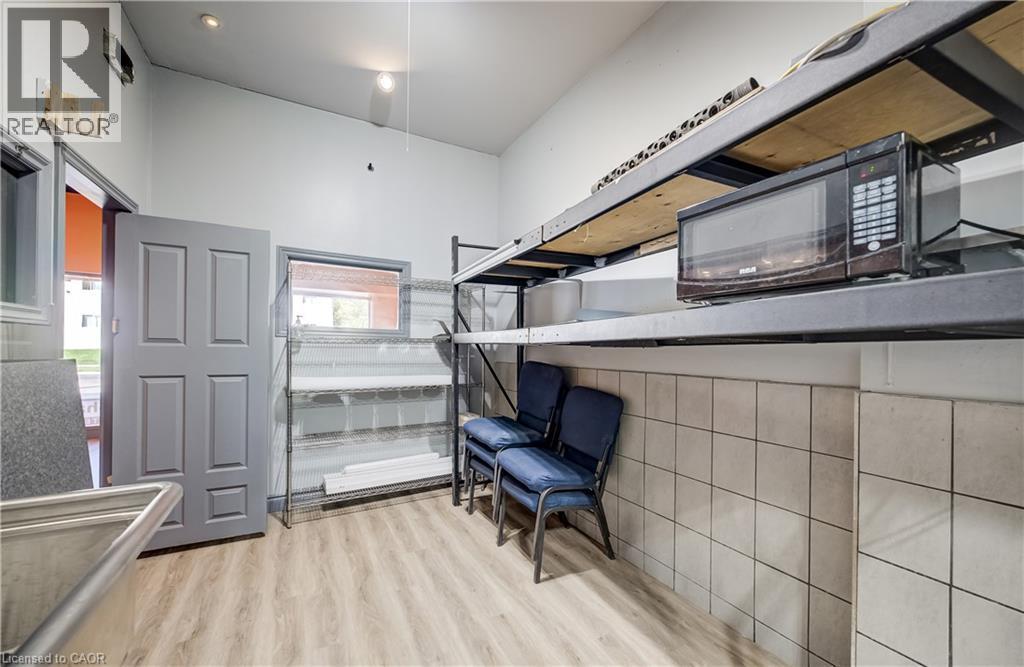 Slanted ceiling with recessed lighting, light wood-finish flooring, half-wall with neutral square tiling, and a gray paneled door - 1118 King Street E, Cambridge, ON