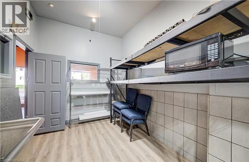 Slanted ceiling with recessed lighting, light wood-finish flooring, half-wall with neutral square tiling, and a gray paneled door - 1118 King Street E, Cambridge, ON 