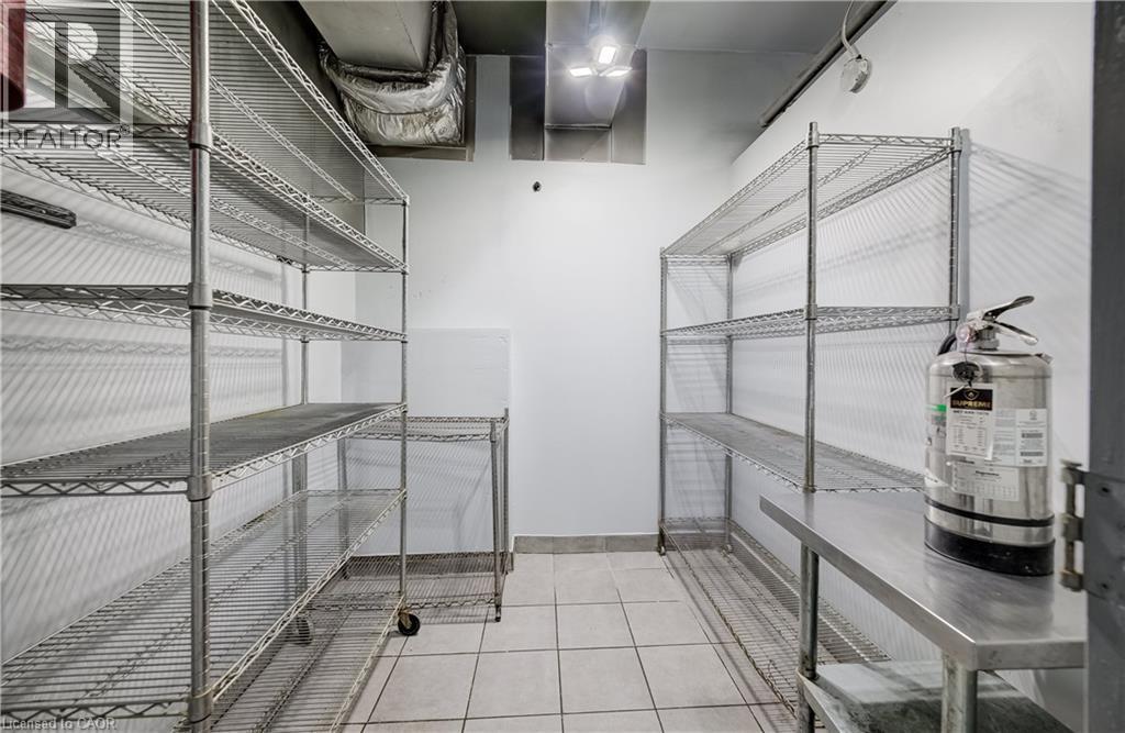 Wire shelving units, tiled flooring, stainless steel countertop, and overhead ductwork - 1118 King Street E, Cambridge, ON