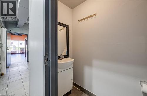 Restroom featuring a wall-mounted mirror, single basin sink with white vanity, and ceramic tile flooring - 1118 King Street E, Cambridge, ON 