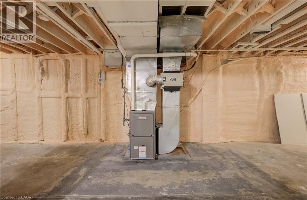 Concrete flooring with exposed ceiling joists, spray foam insulation, and a furnace unit - 1118 King Street E, Cambridge, ON