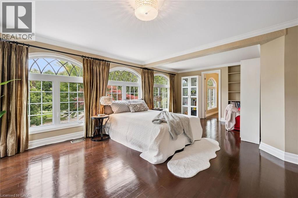 Luxurious primary bedroom suite featuring expansive wood-finish flooring, custom built-in cabinetry, abundant natural light from multi-pane French doors and transom windows, and elegant drapery with d - 334 Coleridge Drive, Waterloo, ON
