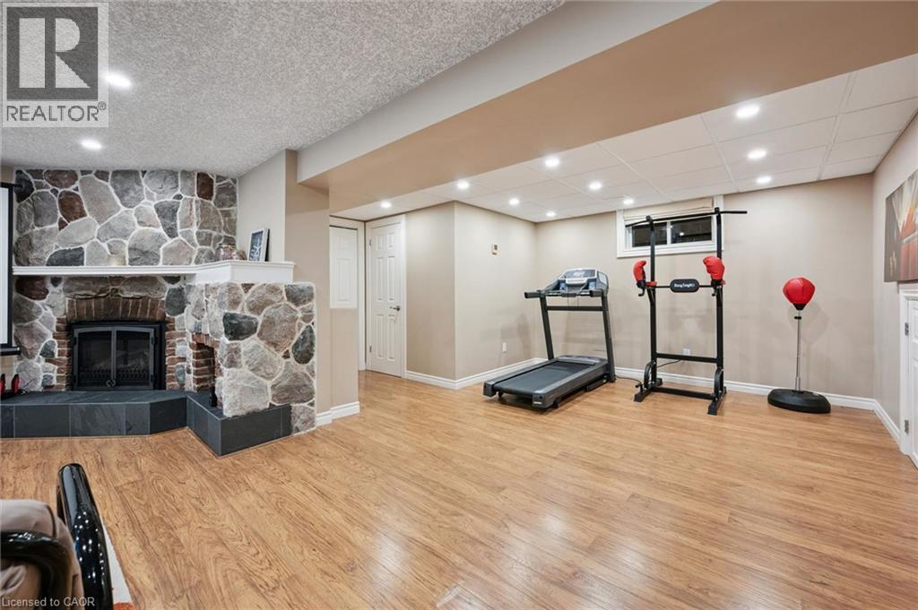 Wood-finish flooring, recessed lighting, and a stone-clad fireplace with a hearth - 334 Coleridge Drive, Waterloo, ON