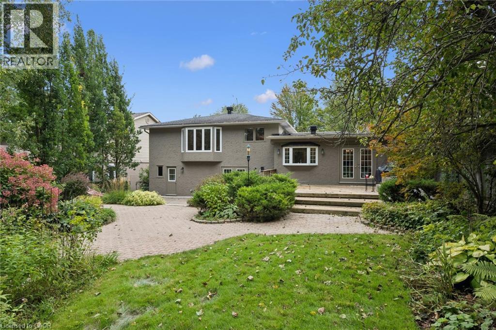 Exterior featuring a brick facade, multi-pane windows, a bay window, and double French doors opening to a hardscaped patio - 334 Coleridge Drive, Waterloo, ON