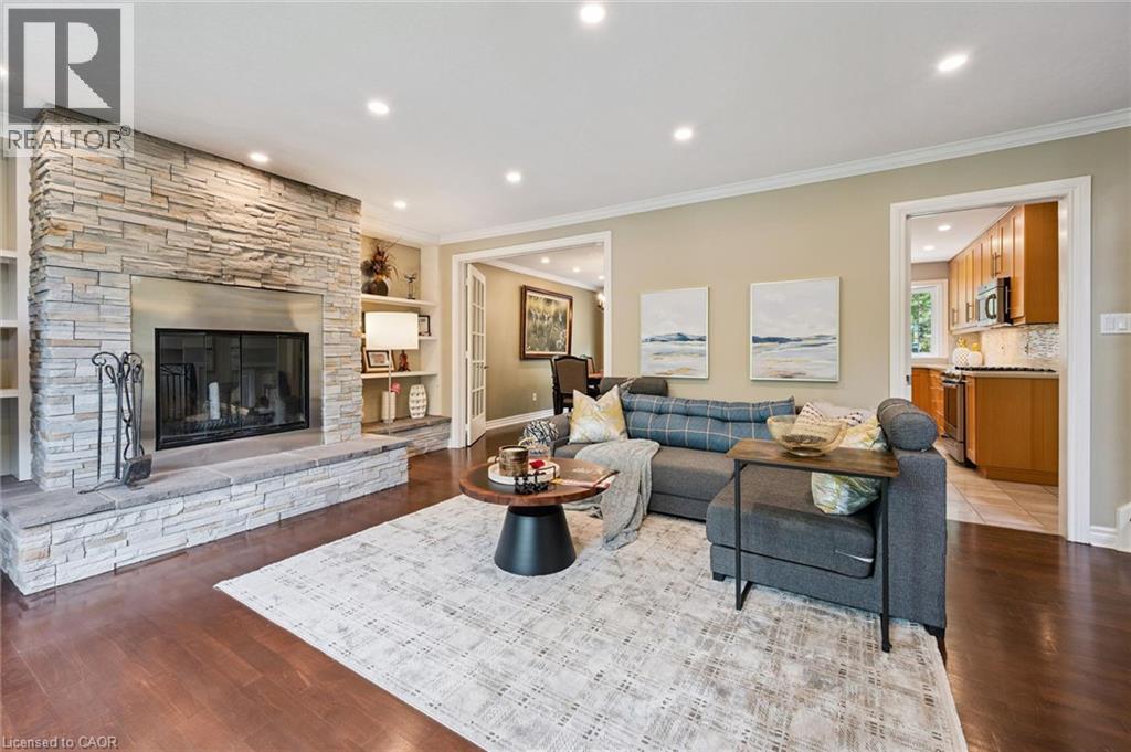 Stone-clad fireplace with a hearth, recessed lighting, wood-finish flooring, built-in shelving, and crown molding - 334 Coleridge Drive, Waterloo, ON