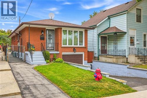 Brick exterior with white-framed windows, an integrated garage, and a front entry porch with black railings - 137 Picton Street E, Hamilton, ON 