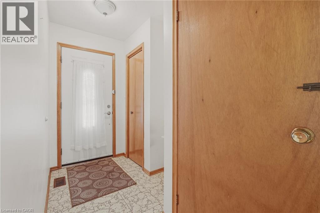 Entryway featuring tile flooring, a white entry door with a decorative glass insert, and natural wood-finish trim - 137 Picton Street E, Hamilton, ON