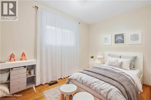 Hardwood-finish flooring, built-in storage unit, and a window with sheer privacy curtains - 137 Picton Street E, Hamilton, ON 