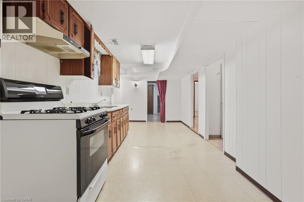 Kitchenette featuring wood cabinetry, white countertops, built-in range hood, and white appliances - 137 Picton Street E, Hamilton, ON