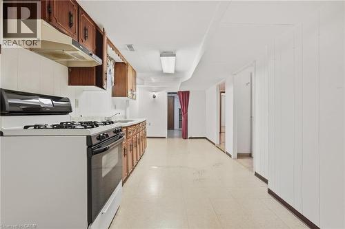 Kitchenette featuring wood cabinetry, white countertops, built-in range hood, and white appliances - 137 Picton Street E, Hamilton, ON 