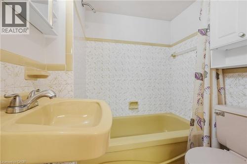 Built-in bathtub, pedestal sink, wall-mounted showerhead, and white wall cabinets - 137 Picton Street E, Hamilton, ON 